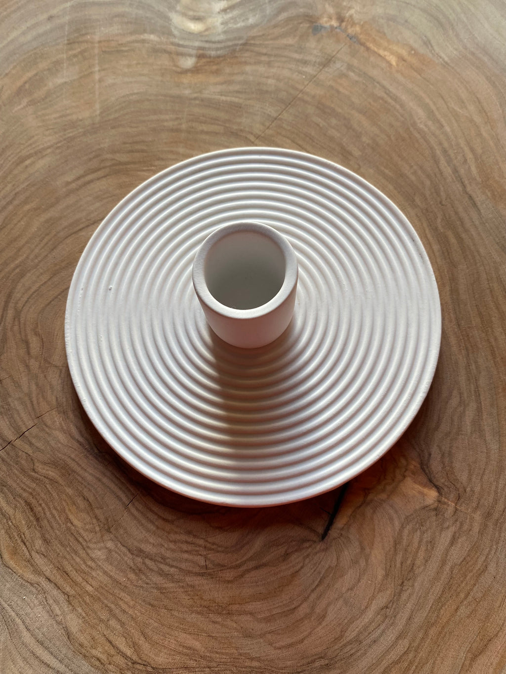 White textured candle holder on a wooden surface