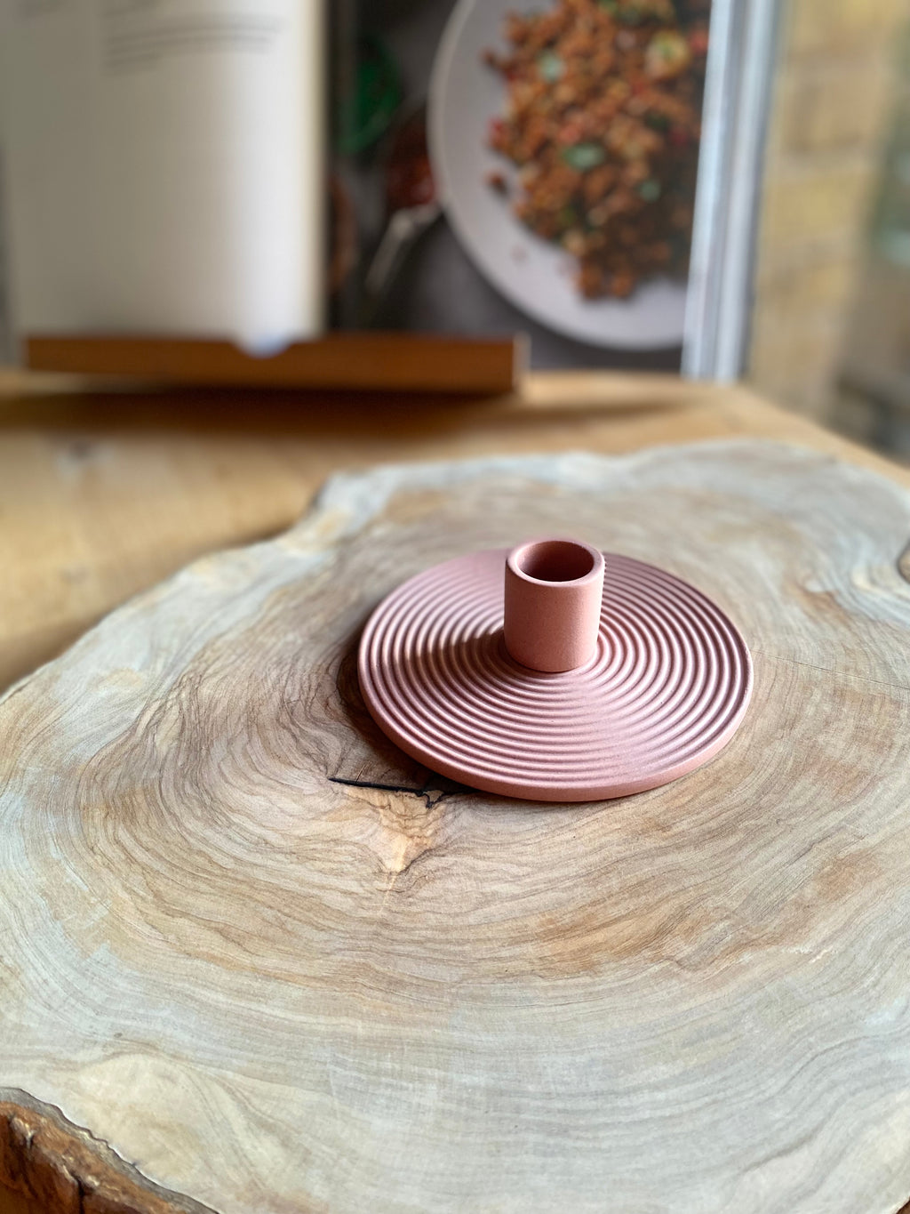 Pink ceramic candle holder on a wooden surface with a blurred background
