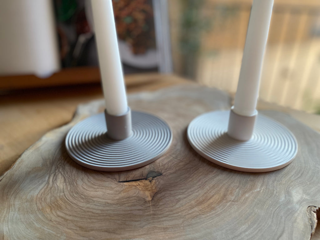 Two candle holders with candles on a wooden surface